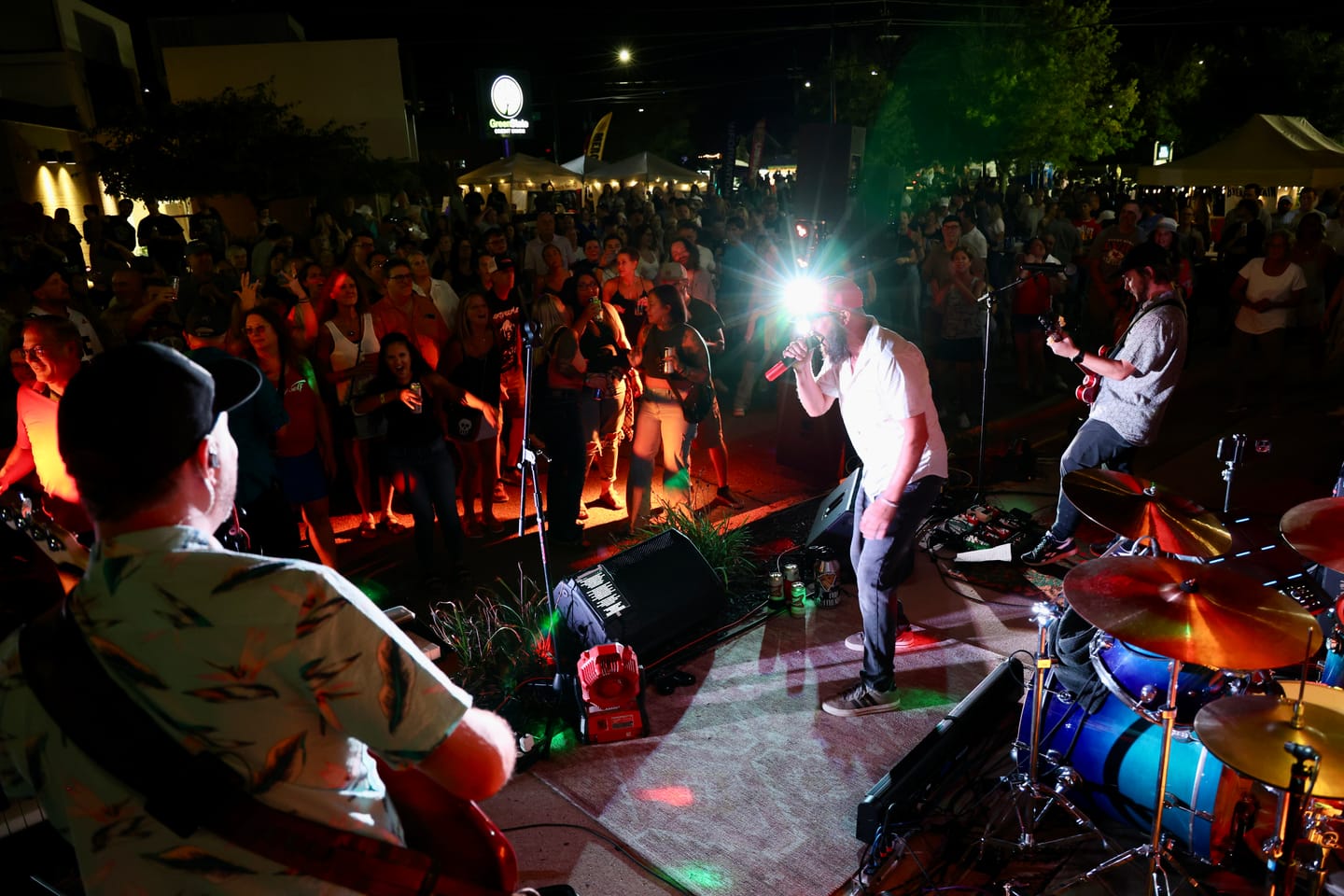 A packed street crowd watching Bad Friends play an outdoor night set at a Des Moines festival